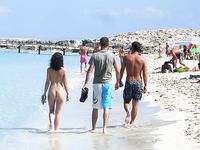 Verspielter Strandmoment nahe den Wellen mit sanftem Zug am Bikini-Unterteil