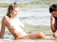 Verspielter Strandmoment nahe den Wellen mit sanftem Zug am Bikini-Unterteil
