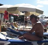 Topless con il perizoma tra gli ombrelloni di una spiaggia affollata
