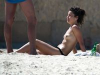 Topless con il perizoma tra gli ombrelloni di una spiaggia affollata