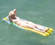 girl nudist kicks up some water at a nude beach