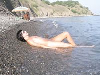 girl nudist kicks up some water at a nude beach
