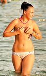 girl nudist kicks up some water at a nude beach