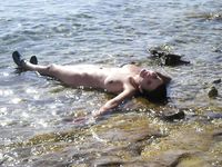 Cappello di piume e bracciali sulla riva sabbiosa di una spiaggia naturista