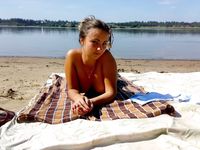 Cappello di piume e bracciali sulla riva sabbiosa di una spiaggia naturista