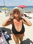 Seduta con un telo su una tranquilla spiaggia naturista