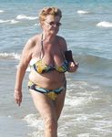Seduta con un telo su una tranquilla spiaggia naturista