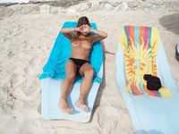 Toalha amarela numa praia rochosa sob o sol quente de verão