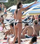 Puszczanie latawca topless w różowym kapeluszu przy brzegu