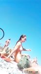 She Ties Her Hair on an Orange Towel at a Pebbled Nude Beach