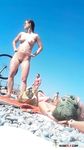 She Ties Her Hair on an Orange Towel at a Pebbled Nude Beach