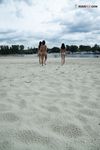 Two Nudists Standing on a Sandy Riverside Beach