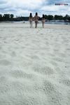 Two Nudists Standing on a Sandy Riverside Beach