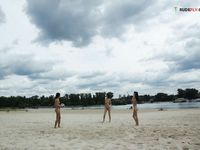 Two Nudists Standing on a Sandy Riverside Beach