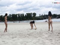Two Nudists Standing on a Sandy Riverside Beach