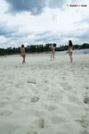 Two Nudists Standing on a Sandy Riverside Beach