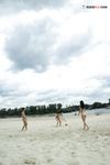 Two Nudists Standing on a Sandy Riverside Beach