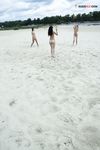 Two Nudists Standing on a Sandy Riverside Beach