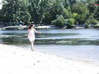 Dvě ženy klečí u břehu na písečné nudistické pláži