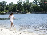 Dvě ženy klečí u břehu na písečné nudistické pláži