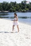 Dvě ženy klečí u břehu na písečné nudistické pláži