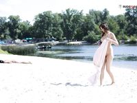Dvě ženy klečí u břehu na písečné nudistické pláži