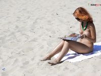 Magazine in Hand After Topless Sunbathing on Sandy Shore