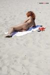 Magazine in Hand After Topless Sunbathing on Sandy Shore