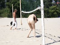 Bending Low to Pick Up a Purple Paddle and Pink Ball on Sand