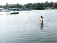 Bending Low to Pick Up a Purple Paddle and Pink Ball on Sand