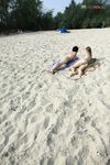 Bending Low to Pick Up a Purple Paddle and Pink Ball on Sand