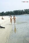 Bending Low to Pick Up a Purple Paddle and Pink Ball on Sand