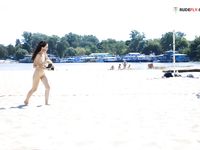Bending Low to Pick Up a Purple Paddle and Pink Ball on Sand