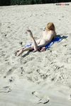 Bending Low to Pick Up a Purple Paddle and Pink Ball on Sand