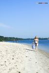Bending Low to Pick Up a Purple Paddle and Pink Ball on Sand