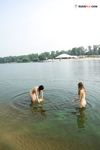 Due naturisti riposano e gesticolano accanto alle acque calme del fiume
