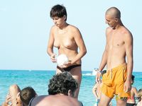 Two dark-haired hotties sit in the sand topless, tanning their slim bodies and firm tits