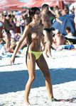 Multiple girls sit around in the sand and enjoy their day with perky tits and firm butts showing completely