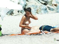 She gets caught on camera sitting topless to tan her slim body and a pair of beautiful, large, natural breasts