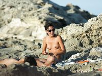 Fat ass nudist mom and her friend are taking time to relax on the beach as they drink water while her curvy body is on display