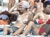 Attractive topless chick smokes and enjoys her day at the beach every year from the time when she first went to the family nudist camp with her mom and dad