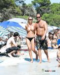 Passeio de casal entre banhistas numa praia topless