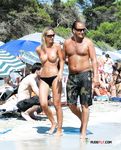 Passeio de casal entre banhistas numa praia topless