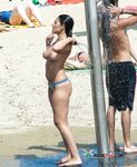 Two Women in Bikinis Chat on a Sunny Beach by the Sea