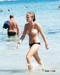 Durch flaches Wasser am hellen Strand – oben ohne