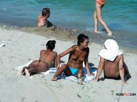 Amateur wives are having a laugh together while on crowded naked beach as they are revealing their natural tits and trying to catch some sun 2