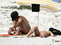 Single brunette is playing cards on the beach in the family nudist camp while showing her natural tits and getting tanned, not knowing that someone is watching 2