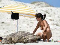 Single brunette is playing cards on the beach in the family nudist camp while showing her natural tits and getting tanned, not knowing that someone is watching 2