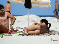 Single brunette is playing cards on the beach in the family nudist camp while showing her natural tits and getting tanned, not knowing that someone is watching 2