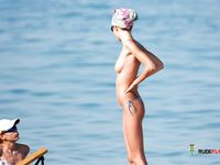 Nudist family relaxes at the beach during a hot summer day